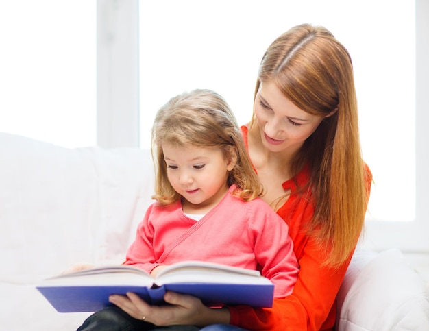 family, children, pre-school and happy people concept - happy mother and daughter with book