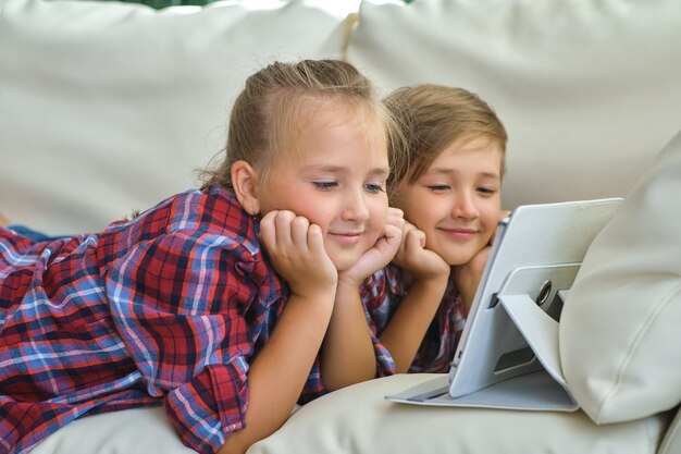 가족, 어린이, 기술, 가정 개념 - 거실 소파에 태블릿 Pc를 들고 웃고 있는 형제 자매