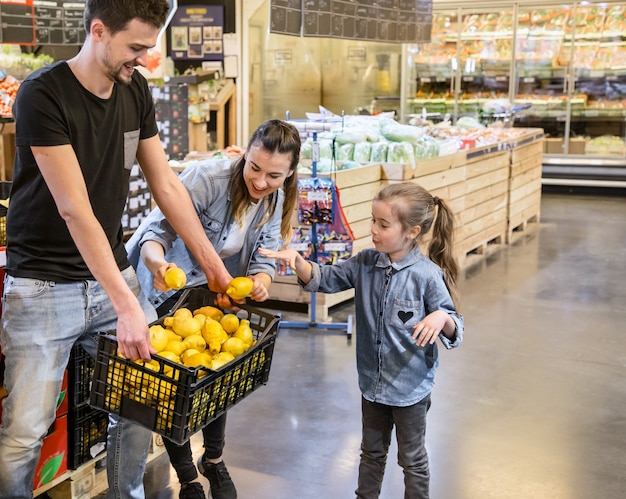 Famiglia che sceglie i limoni e la frutta nel supermercato