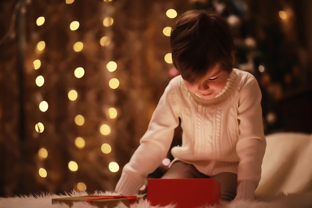 暖炉のそばでクリスマスイブの家族 クリスマス プレゼントを開く子供たち クリスマス ツリーの下でギフト ボックスを持つ子供たち 伝統的な暖炉のあるリビング ルームの装飾 家で居心地の良い暖かい冬の夜