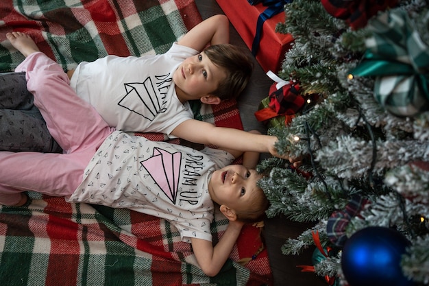 크리스마스 이브에 가족입니다. 아이 선물 상자와 함께 크리스마스 트리 아래 아이 들. 전통적인 벽난로가 있는 장식된 거실. 아늑하고 따뜻한 겨울 저녁 집.