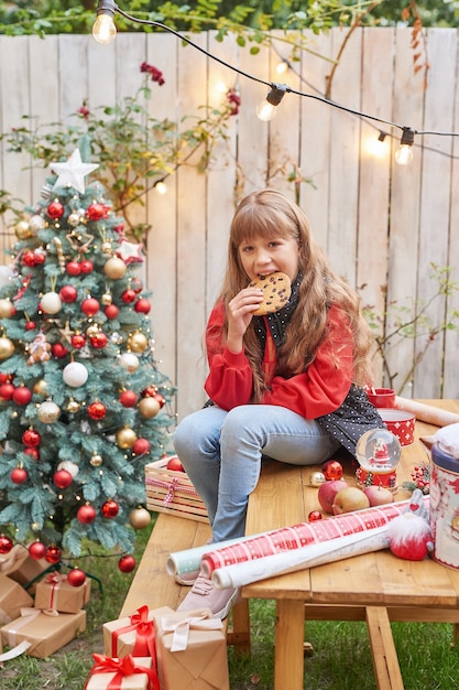 7月の家族のクリスマス。贈り物とクリスマスツリーの近くの女の子の肖像画。松を飾る赤ちゃん。冬の休日と人々の概念。メリークリスマスとハッピーホリデーグリーティングカード。クリスマスの子供