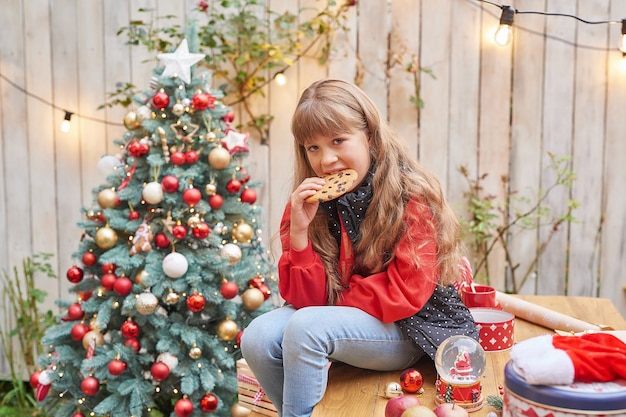 Семейное Рождество в июле. Портрет девушки возле елки с подарками. Детские украшения из сосны. Зимние праздники и люди концепции. Поздравительная открытка с Рождеством и праздниками. Рождественский ребенок