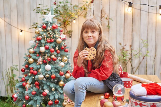 7月の家族のクリスマス。贈り物とクリスマスツリーの近くの女の子の肖像画。松を飾る赤ちゃん。冬の休日と人々の概念。メリークリスマスとハッピーホリデーグリーティングカード。クリスマスの子供