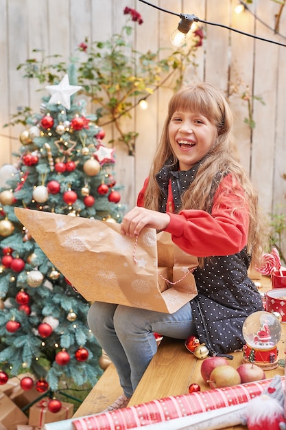 7月の家族のクリスマス。贈り物とクリスマスツリーの近くの女の子の肖像画。松を飾る赤ちゃん。冬の休日と人々の概念。メリークリスマスとハッピーホリデーグリーティングカード。クリスマスの子供