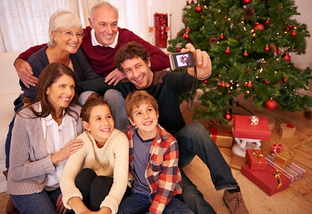 家族のクリスマス パーティーと携帯電話の自撮り祭りの季節や休日のお祝い肖像画の笑顔と祖父母の子供と両親は家で一緒に思い出の写真のポーズや写真の笑顔を祝う