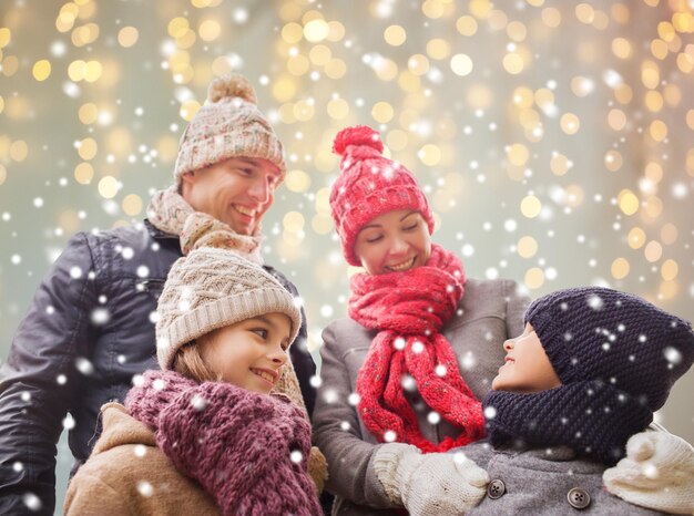 Фото Концепция семьи, рождества, зимы, сезона и людей - счастливая семья на открытом воздухе на фоне праздничных огней и снега