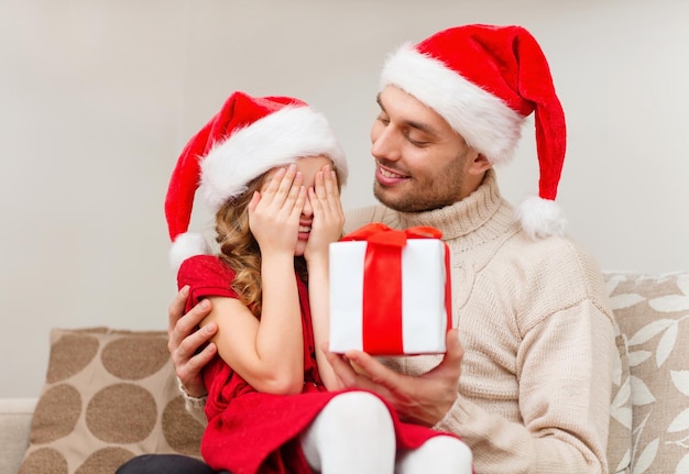 семья, рождество, рождество, счастье и концепция людей - улыбающаяся дочь с закрытыми глазами ждет подарка от отца