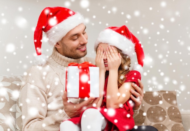 家族、クリスマス、クリスマス、冬、幸福と人々の概念-目を閉じて笑顔の娘がfatheからのプレゼントを待っています