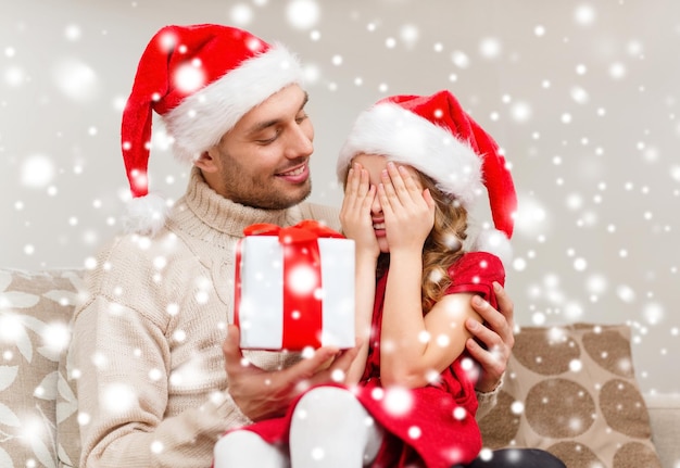 family, christmas, x-mas, winter, happiness and people concept - smiling daughter with closed eyes waiting for a present from fathe