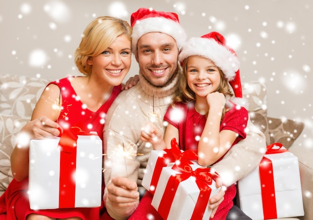 family, christmas, x-mas, winter, happiness and people concept - smiling family in santa helper hats with many gift boxes and bengal lights