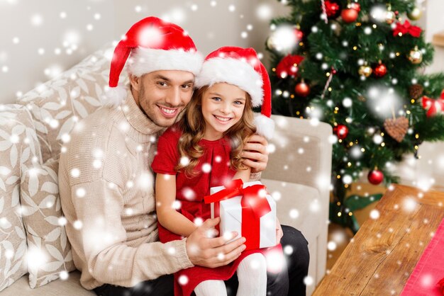 가족, 크리스마스, 크리스마스, 겨울, 행복, 그리고 사람들의 개념 - 선물 상자를 들고 산타 도우미 모자를 쓰고 웃고 있는 아버지와 딸