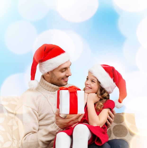 Famiglia, natale, natale, inverno, felicità e concetto di persone - padre sorridente che dà scatola regalo figlia