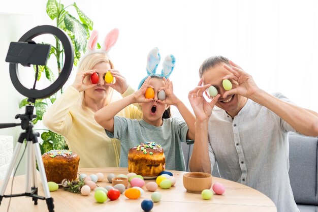 family communicates online using special program with friends on Easter holiday. Web conference via video call on tablet to his colleagues. Decorated table with flowers and colorful eggs.