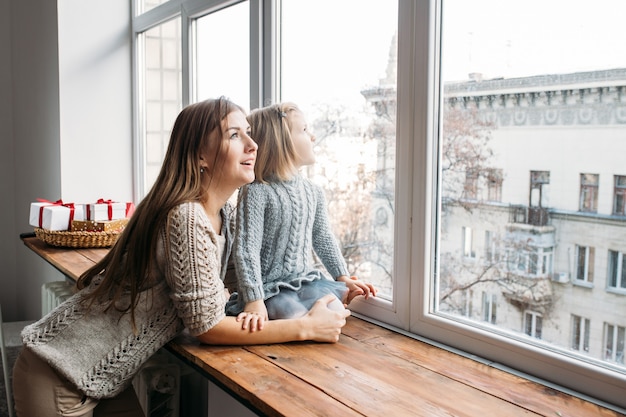 Foto concetto di famiglia. madre e figlia che guardano nella finestra.