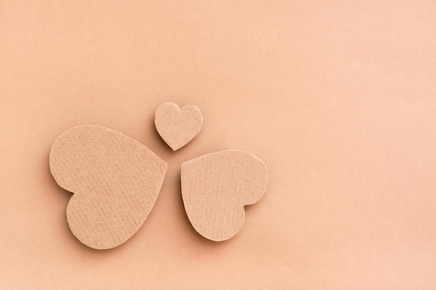 Family concept. Three cardboard hearts - dad, mom and child stand in a circle on a beige background. Top view.