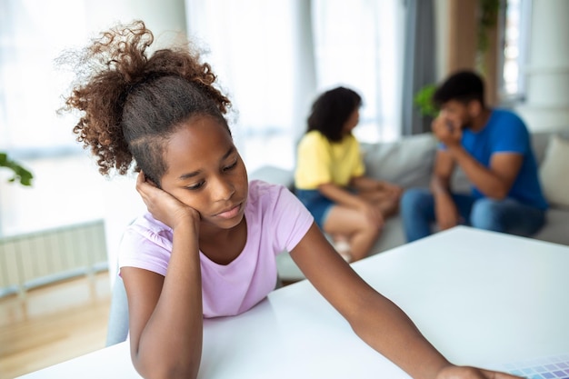 Family Conflicts Sad little black girl listening to her parents arguing in the background upset girl don't want to hear quarrel stressed kid