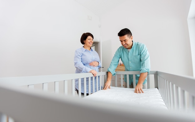 family couple arranging baby bed with mattress