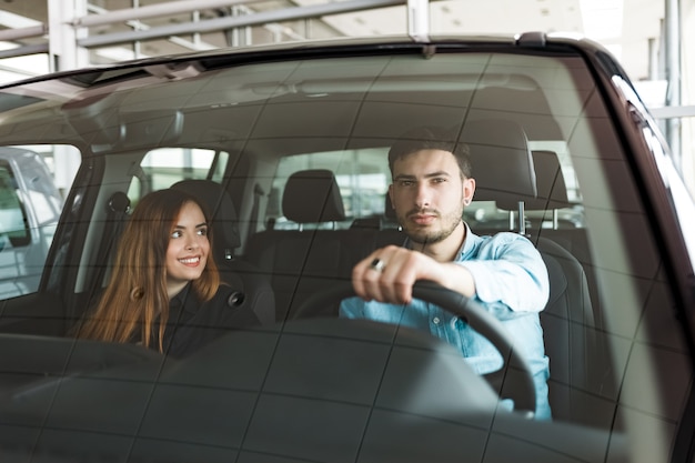 family couple in their new car at the auto dealership