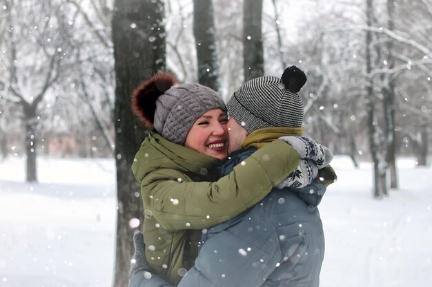 家族のカップルは冬の雪を歩く