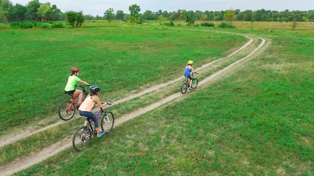 Family cycling on bikes outdoors aerial view from above, happy active mother with children have fun, family sport and fitness