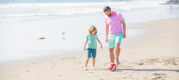 ビーチの幸せでボールを遊んでいるパパの男と子の男の子の家族