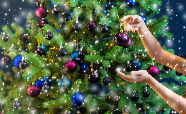 A family decorates a Christmas tree at night. Selective focus. Holiday.