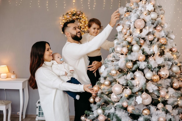 Семья вместе украшает рождественскую елку дома.