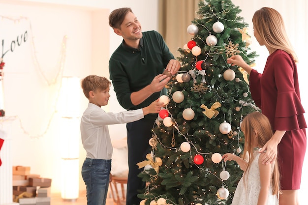 Family decorating beautiful Christmas tree in room