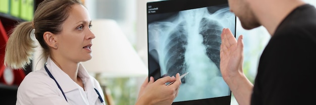 Family doctor shows xray picture to patient at appointment in hospital therapist explains lungs