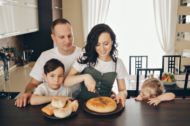 The family eats cakes. dinner at the bakery. feast in the kitchen. the butchering of the food. a woman cuts a pie with a knife