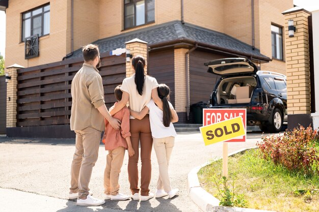 Family embracing each other in front of new house