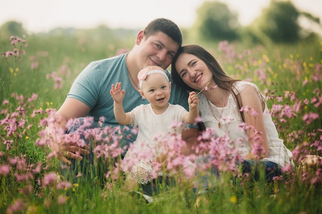 Foto famiglia che gode della vita insieme nel campo estivo con fiori selvatici.