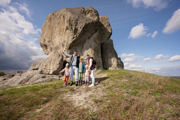 Family exploring nature Children with parents wear backpack hiking against big stone in hill Pidkamin Ukraine