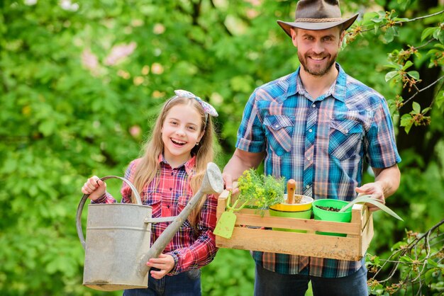 Family farm spring village country ecology Watering can and shovel little girl and happy man dad earth day father and daughter on ranch Beautiful florist at work hello summer