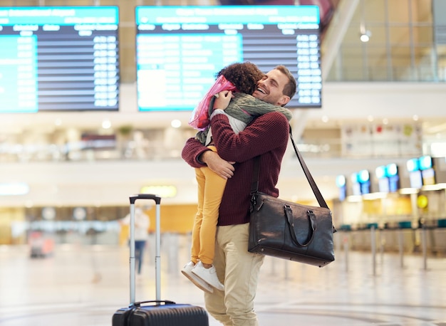 空港旅行で家族の父と子が抱擁し、飛行後に男に挨拶する女の子 ターミナルで荷物を持った幸せと愛 幸せなケアと旅行バッグとの絆、そして再会とともに帰宅