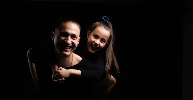 a family. father and daughter on black background