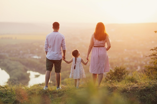 Family father mother and little daughter standing on the hill