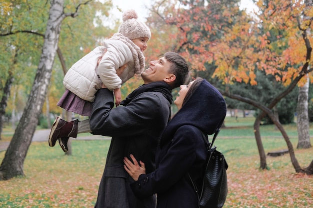 Family father and mother on a walk in the park playing with daughter.