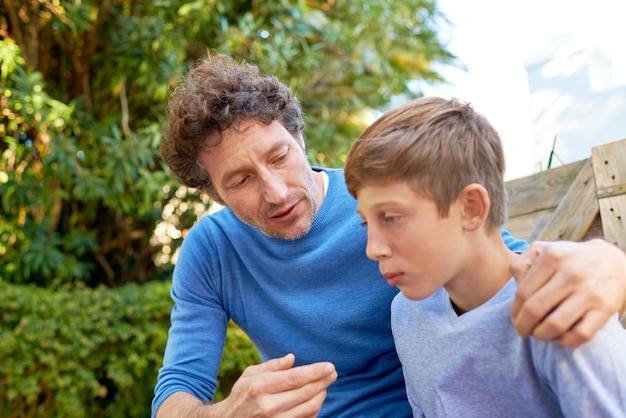 Family father talking with son in backyard bonding with love and care communication and relationship Man with sad teen boy help with advice at home and outdoor together with trust and support