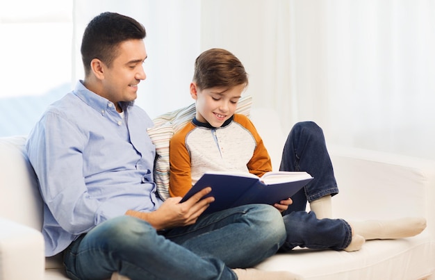 family, fatherhood, generation, literature and people concept - happy father and son reading book at home