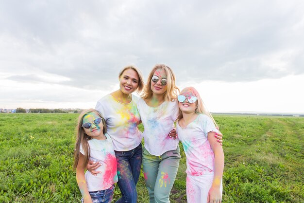 Family, festival of holi and holidays concept - portrait of mothers and daughters covered in paint