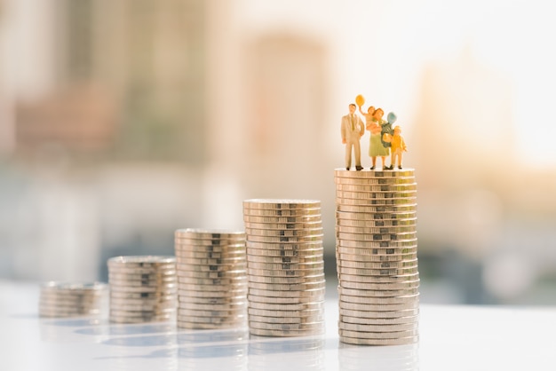 Photo family figure standing on top of coin stack.