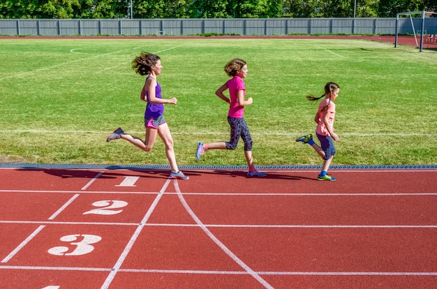 Foto la forma fisica, la madre e i bambini della famiglia che corrono sulla pista dello stadio, sull'addestramento e sui bambini mettono in mostra il concetto sano di stile di vita