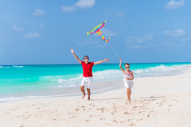 Family flying kite together at tropical white beach