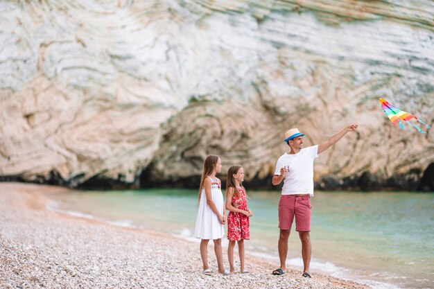 Family flying kite together at tropical white beach