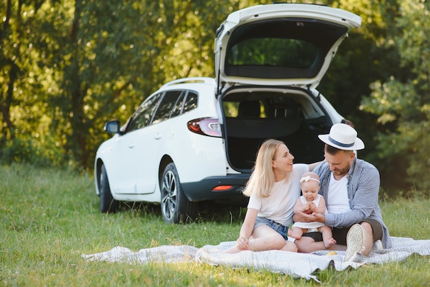 Family in a forest. People by the car. Sunset background.