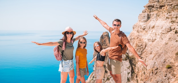 Family of four hiking on a cliff above the sea