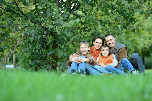 芝生に座ってポーズをとる 4 人家族