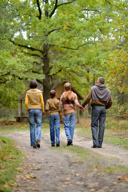 Foto famiglia di quattro persone che camminano nella foresta d'autunno